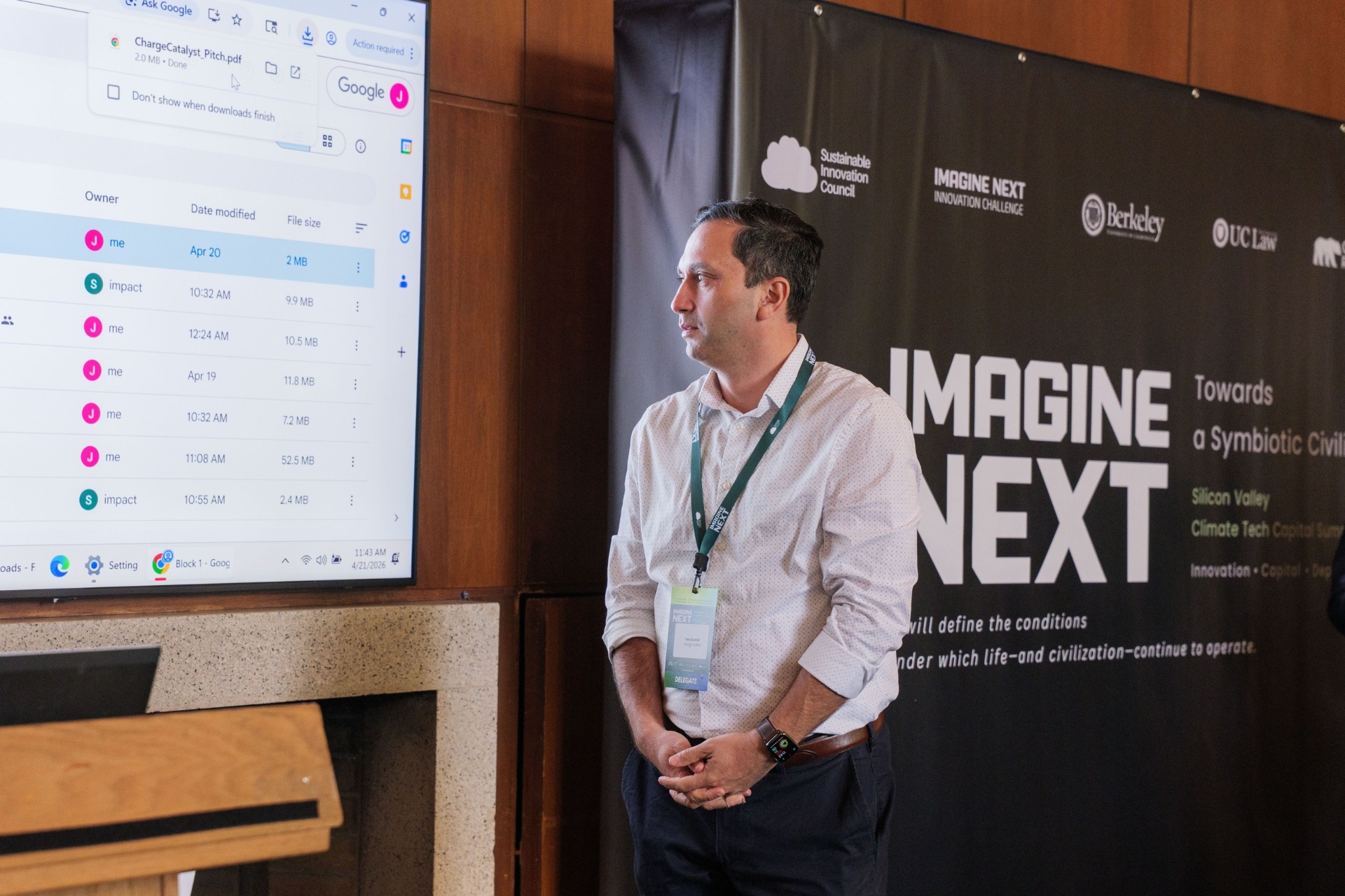 Delegate listening beside the large Imagine Next Innovation Challenge backdrop