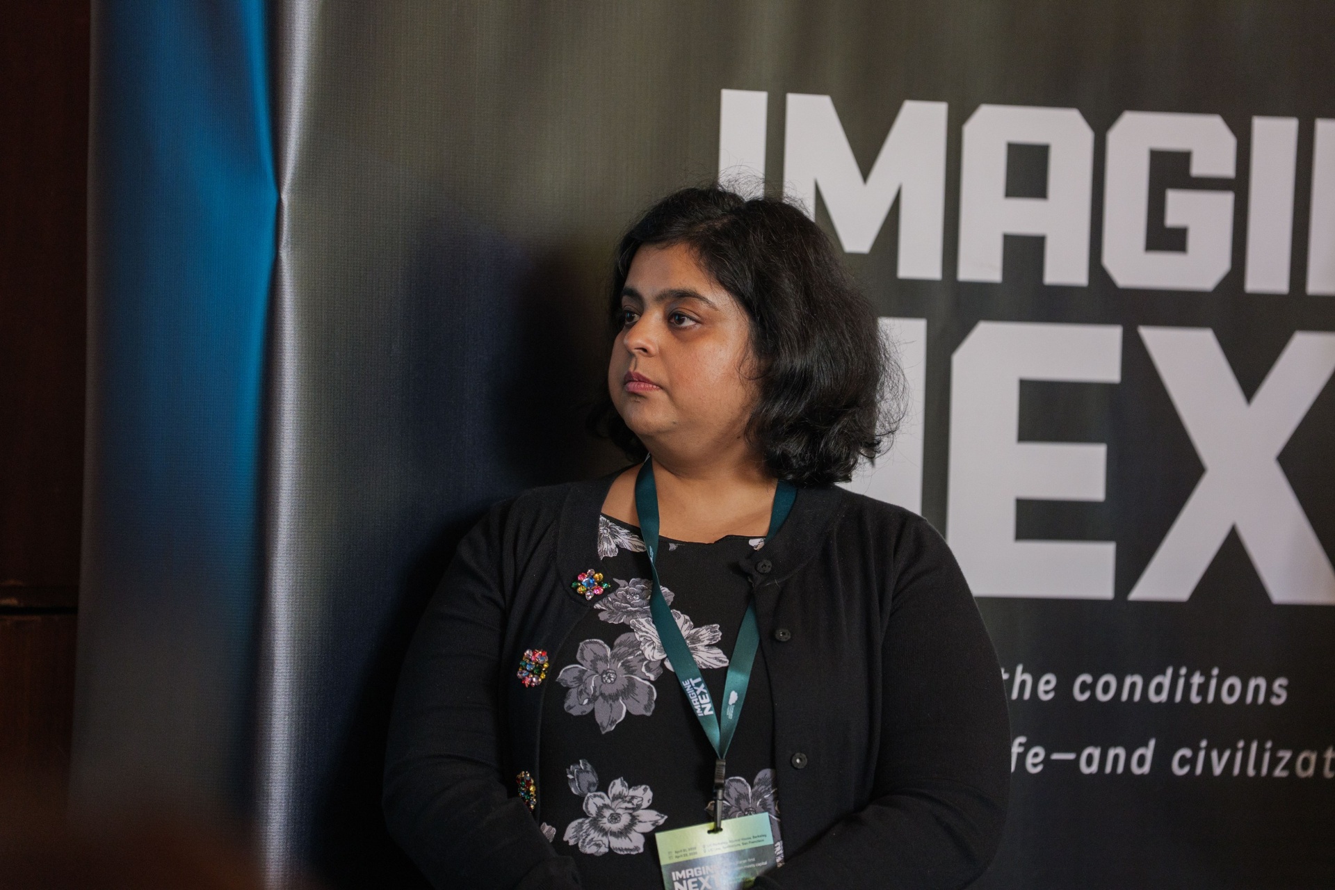 Delegate beside the Imagine Next backdrop at the Alumni House