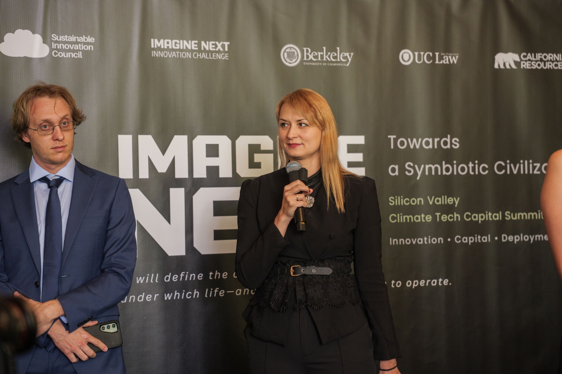 Host introducing the jury panel beside the Imagine Next backdrop