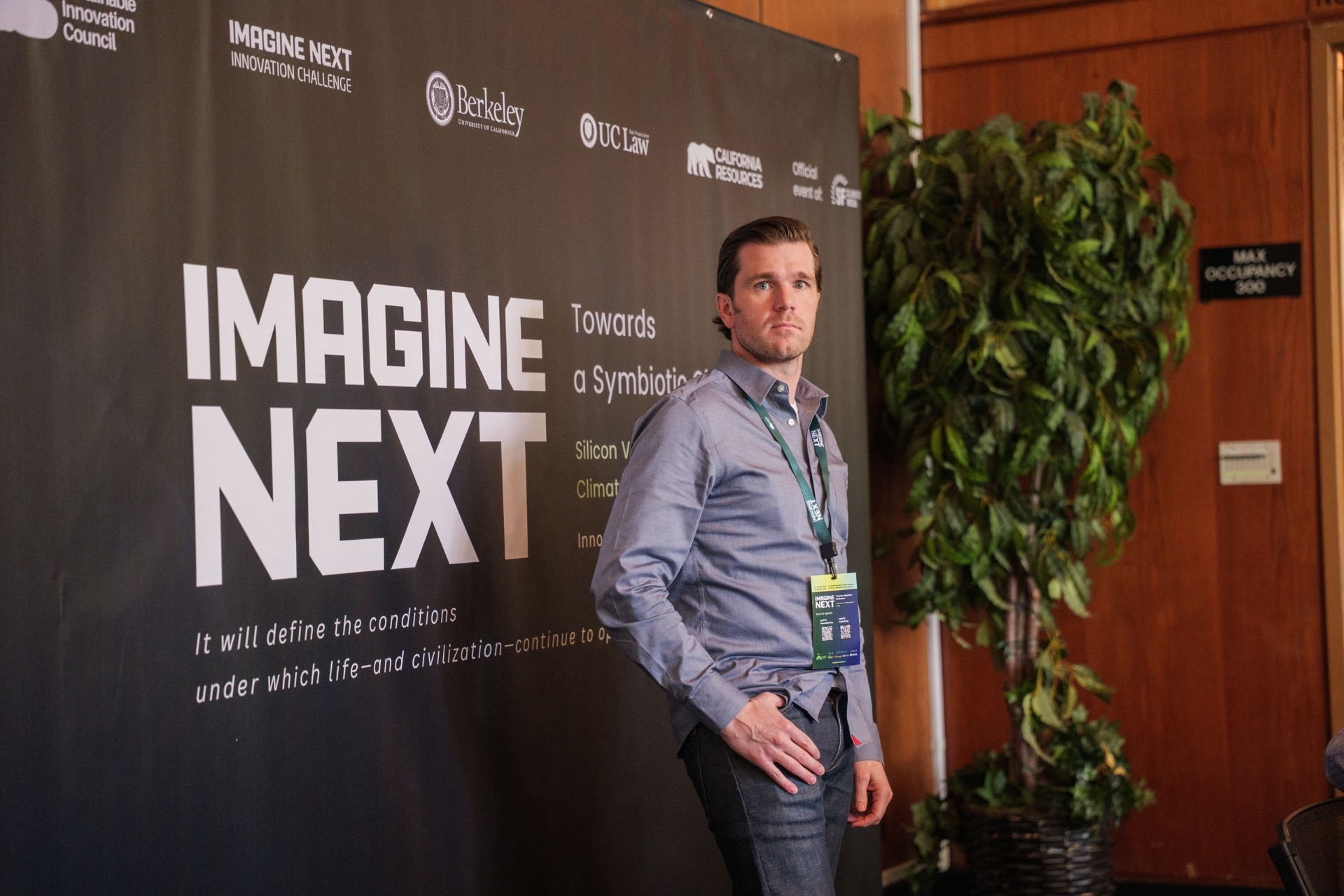 Delegate beside the large Imagine Next Innovation Challenge backdrop